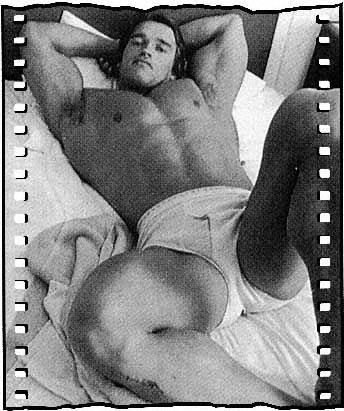 Arnold Schwarzenegger in bed in his underwear with film strip sprocket holes