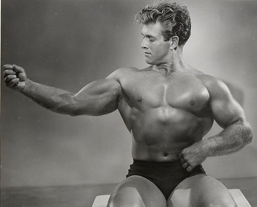 1950s bodybuilder Bud Counts poses in black trunks for Atheletic Model Guild.