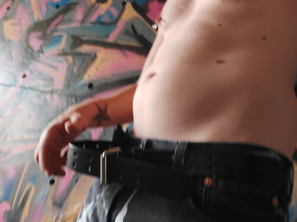 Jack Drago's belt and tattoos against the graffiti under the bridge.
