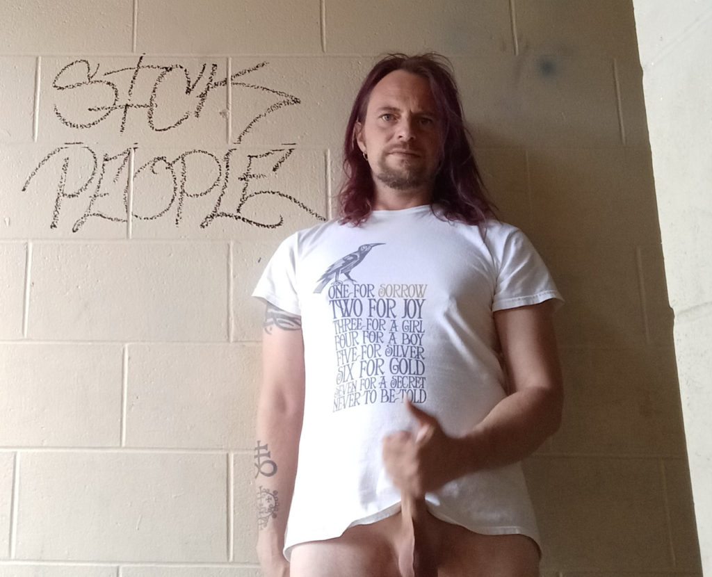 Jack Drago pumps dick in front of a graffito that says "Sick People" 