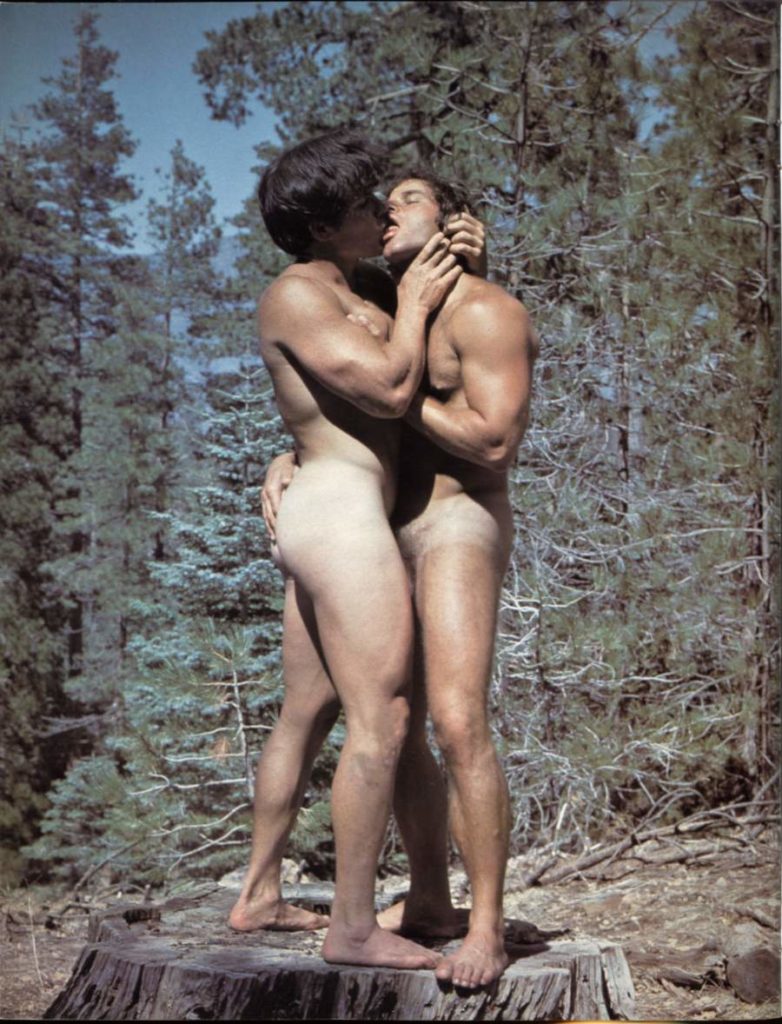 David Carter kisses Richard Miller on a stump in a pine forest, full color.