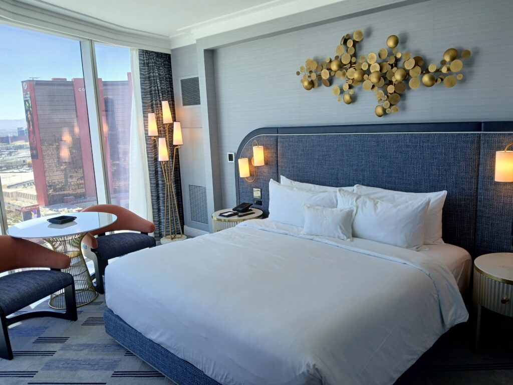 Typical suite at the Fontainebleau Las Vegas with a view of Resorts World and a blue and gold decor.