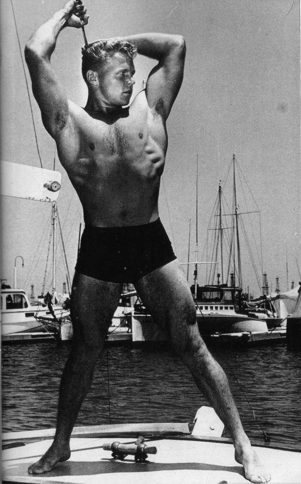 Lance Arlen poses on the deck of a boat in the marina in black and white circa 1962.