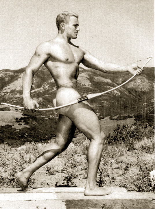 Mike Sill poses fully nude with a bow in black and white.